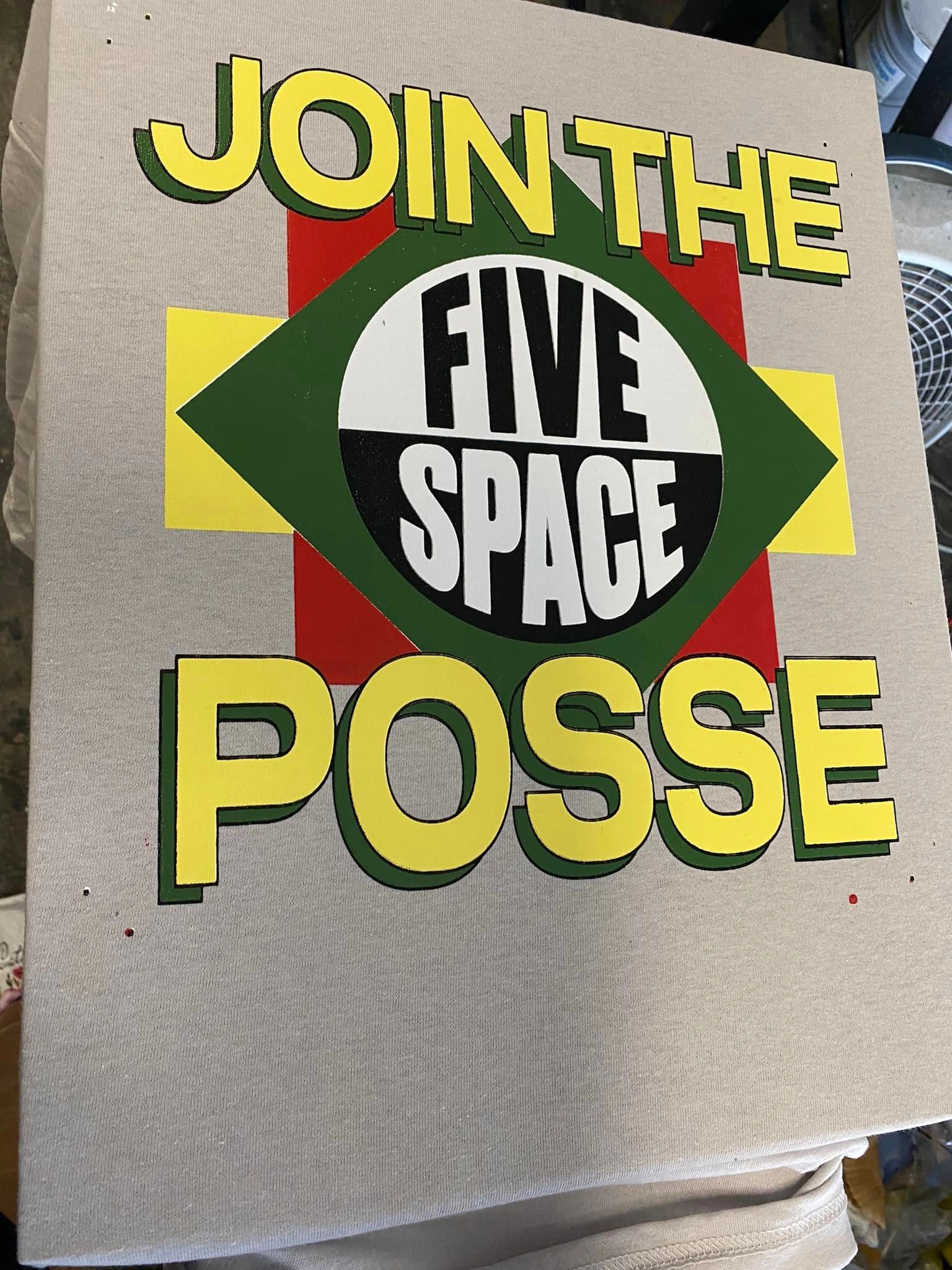 A white tee combines green, gold and black with the words “Join the Five Space Posse.” The graphic fills the front of the garment.