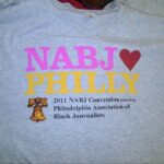 A light-colored tee carries bright “NABJ Philly” lettering and smaller event text. This small surviving image records the original multicolor design.