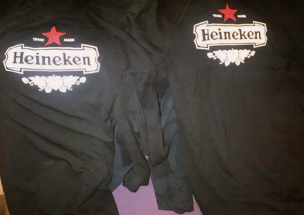 Black garments display Heineken branding with a red star and white lettering, shown in two print placements.